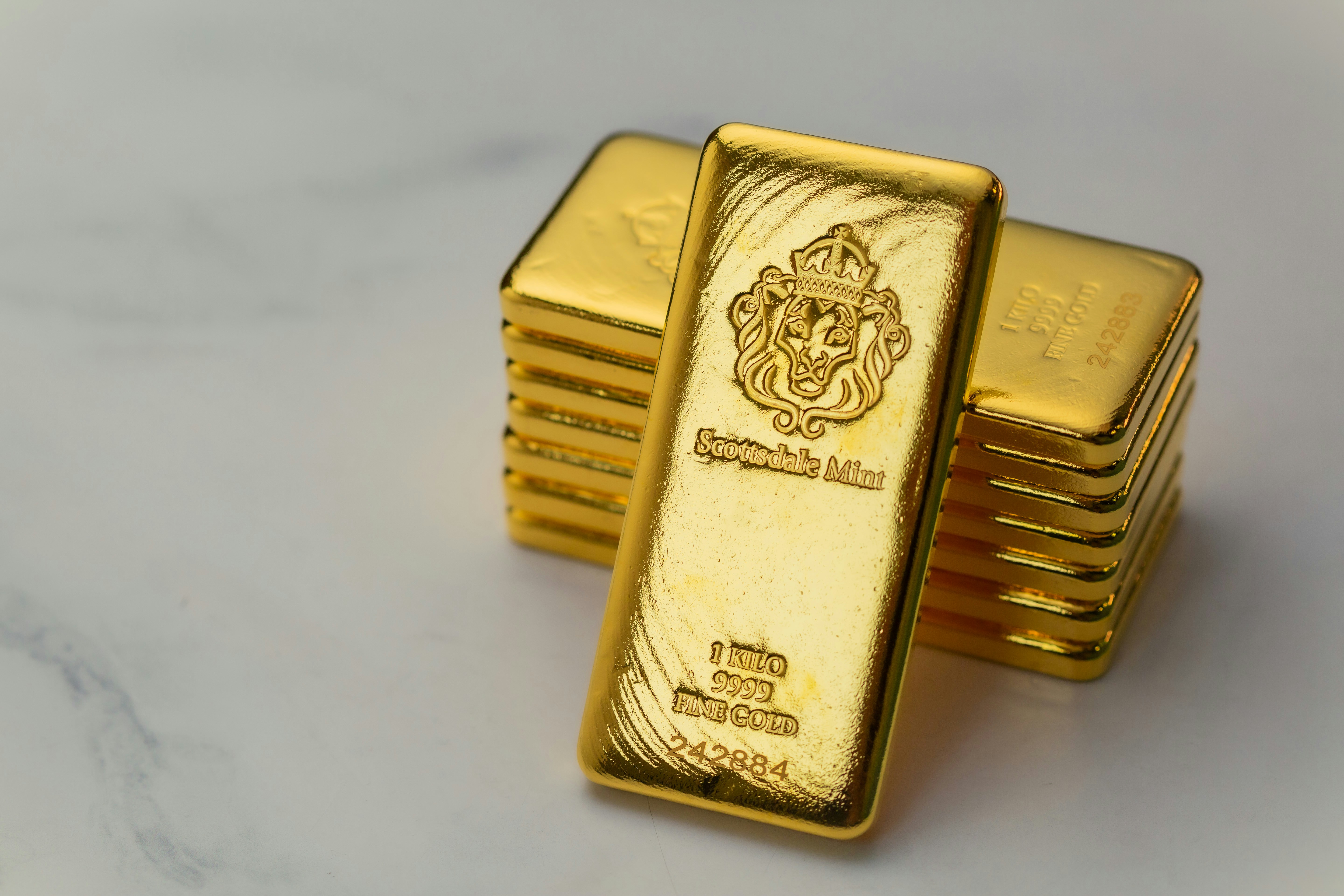 Scottsdale Mint 1 Kilo Gold Bullion Bars sitting on a simple textured backdrop. Each bar is pure 9999 Fine and made from gold precious metals. Please give a shoutout to Scottsdale Mint if able! Shop online for the most beautiful bullion at ScottsdaleMint.com!